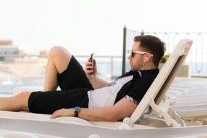 Mann på solseng med mobiltelefon